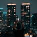 A person photographing Jakarta's illuminated skyscrapers during a vibrant city night.