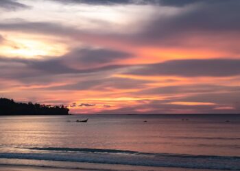 Beautiful sunset over the sea in Phuket, Thailand with colorful clouds and calm water.